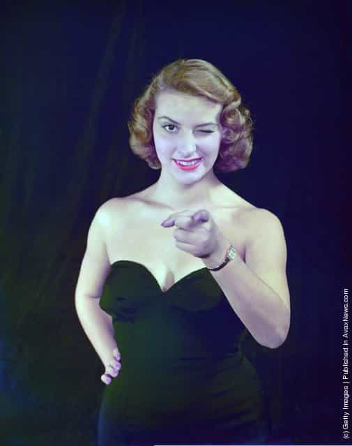 A portrait of a model pointing and winking at the camera, circa 1950