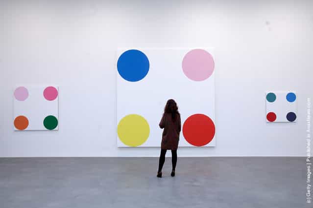 An employee looks at the artwork 4-Chlorephenol, 2008, part of the artist Damien Hirsts exhibition The Complete Spot Paintings