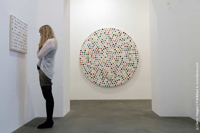 An employee looks at the artwork Hydroquinone, 2006, part of the artist Damien Hirsts exhibition The Complete Spot Paintings