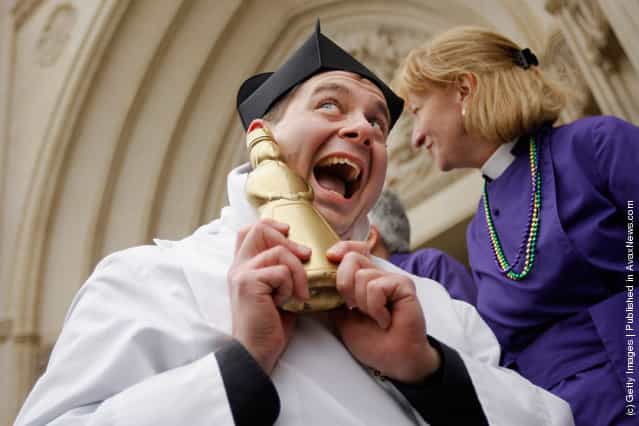 Father Matthew Hanisian, assistant rector at St. Albans Parish, poses with his gold-painted syrup bottle trophy after winning a pancake race during the Shrove Tuesday, or Mardi Gras, tradition at the National Cathedral