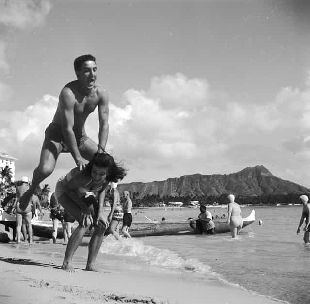 Bert and Ellie Lang, a young American couple on their honeymoon in Hawaii play leap-frog on Honolulu's Waikiki beach. In the background is the extinct volcanic crater of Diamond Head, circa 1955. (Photo by Orlando)