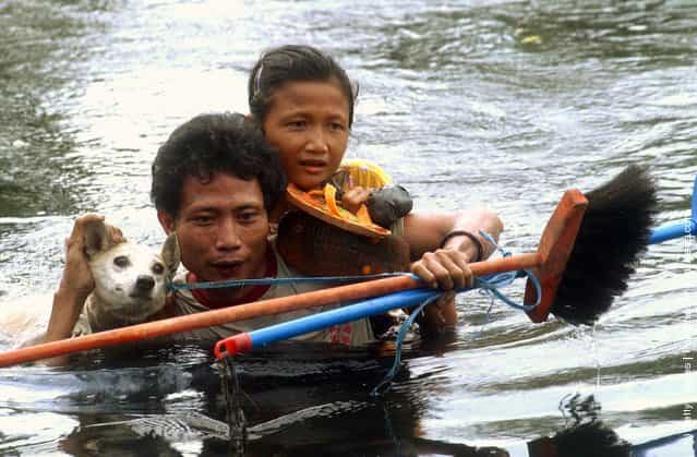 A man, girl and dog cross deep water at Sirombu village December 29, 2004 in Nias, North Sumatra, Indonesia