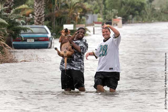 Two youths carry their dog down the flooded street after Hurricane Katrina dumped as much as 15 inches of rain as it passed over this communinty south of Miami August 26, 2005 in Homestead, Florida