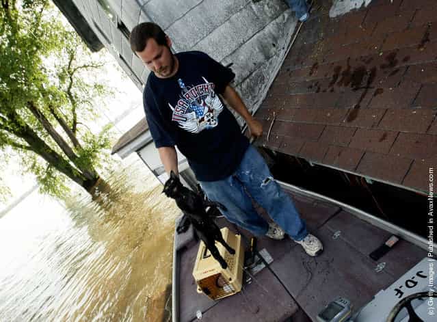 Jerry Ford rescues a wet cat from a house June 18, 2008 as floodwaters overtake the town of Oakville, Iowa