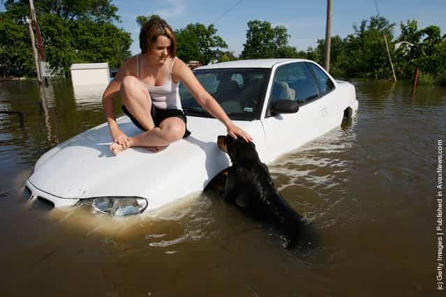 Alexae Dunn pets her dog Lady while sitting on a car surrounded by flood waters near her home June 23, 2008 in South Shore, Missouri