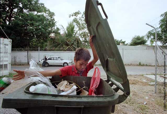 An East Timorese boy picks through the trash can at a local hotel looking for cans to recycle