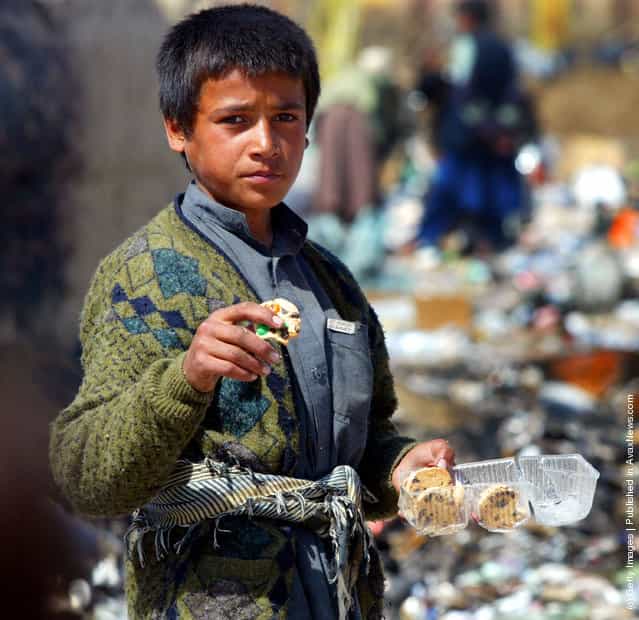 An Afghan boy eats cookies he found at the garbage dump after finding them in the discarded garbage from the Bagram airbase in Afghanistan