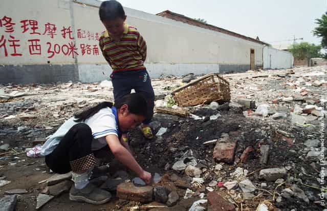 Migrant children from Henan province play in a puddle near a garbage site next to their home in northern Beijing, China