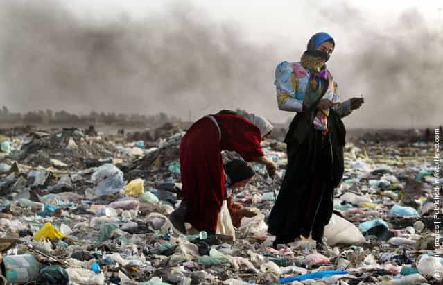 A woman pauses as a girl searches through trash in the garbage dump where their family lives in Baghdad, Iraq