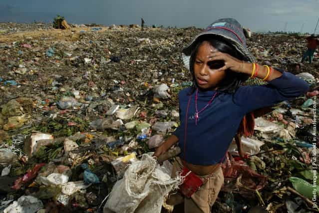 A Cambodian girl goes through the garbage dump looking for things to recycle in order to survive