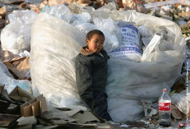 A Chinese kid of migrant workers plays at a refuse dump