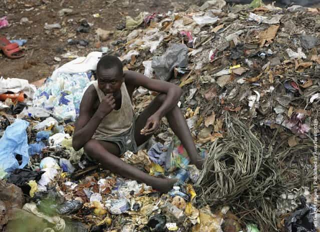 A Man eats garbage from a pile in Freetown, Sierra Leone