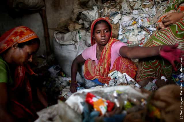 Women work for a recycling business by sorting through trash for usable paper products in Dhaka, Bangladesh