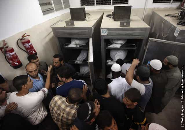 Palestinians stand in the morgue next to the bodies of six militants killed in an Israeli airstrike