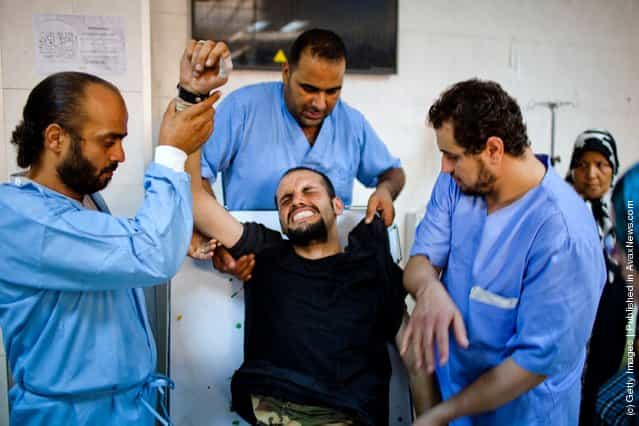 A Libyan Rebel fighter grimaces as he receives medical attention after being brought in with a gun wound to his torso at the Tripoli Central Hospital