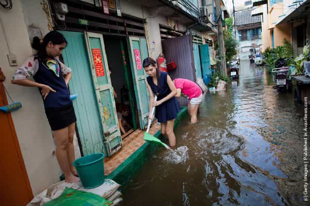 Thai residents scoop water out of their homes on a flooded street in China Town near to to the overflowing Chao Phraya river