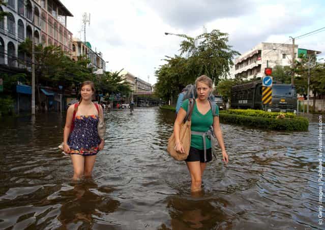 American students from the Thammasat University walk down newly flooded streets near the Chao Phraya river
