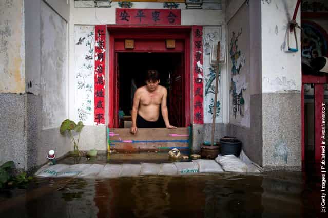 A man looks down at rising flood waters encroaching on a Chinese temple in China Town near to the overflowing Chao Phraya river