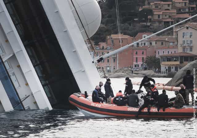 Rescuers work on the cruise ship Costa Concordia as lies stricken off the shore of the island of Giglio