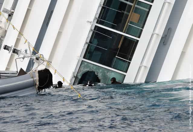 Rescuers work near the cruise ship Costa Concordia as lies stricken off the shore of the island of Giglio