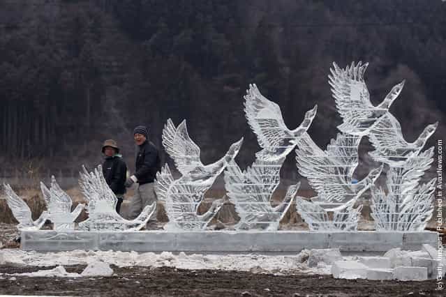 Two men walk past an ice scultpture carved for the anniversary of last years deadly earthquake and tsunami on March 11, 2012 in Rikuzentakata, Japan