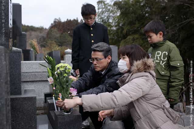 Keiko Takeda, husband Yoshihiro and two sons Seiya and Shunma place flowers at the gravesite of her parents, Tetsji and Hiroko and uncle Hiroo and aunt Moto at the Jodoji Temple on March 11, 2012 in Rikuzentakata, Japan
