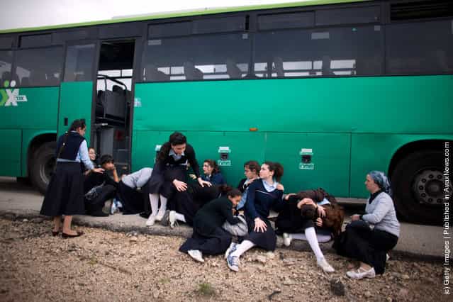 Israeli school girls take cover next to a bus during a rocket attack from the nearby Gaza Strip