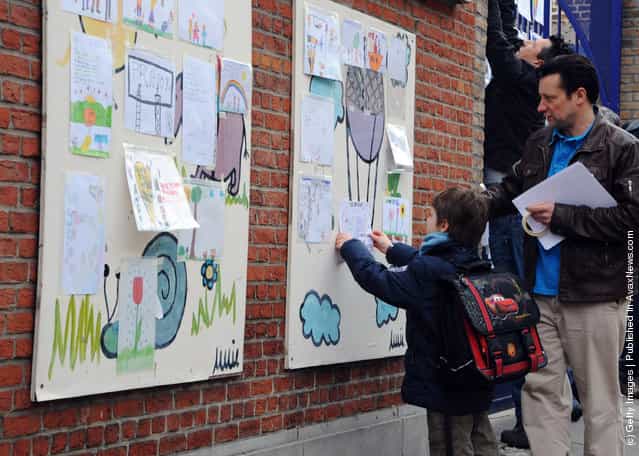 A school child puts up a picture at the gates of Sint Lambertus School, following a bus crash that killed 22 children in Switzerland, on March 14, 2012 in Heverlee, Belgium