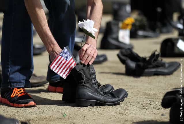 An Iraq war veteran placed an American flag in a pair of combat boots that are part of the Eyes Wide Open exhibit in front of San Francisco City Hall