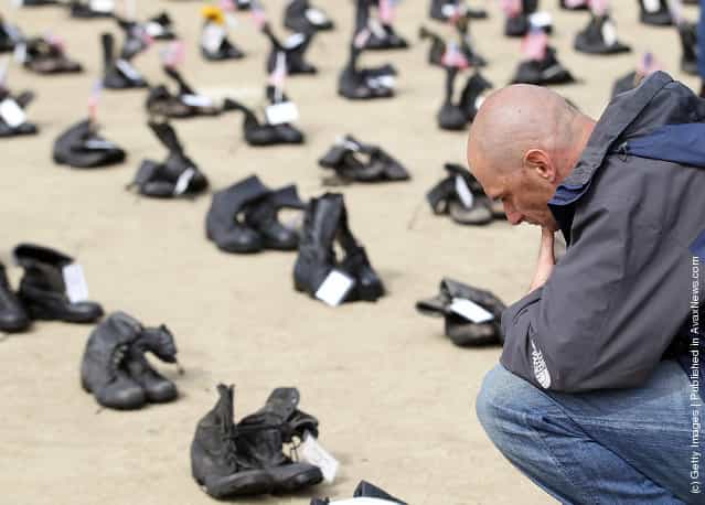 A man pauses as he looks at rows of combat boots that are part of the Eyes Wide Open exhibit in front of San Francisco City Hall