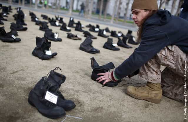 Iraq war veteran Scott Olsen adjusts rows of combat boots that are part of the Eyes Wide Open exhibit in front of San Francisco City Hall