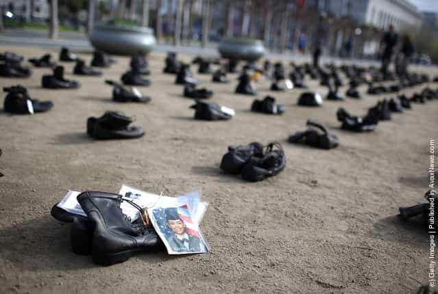 A photograph is displayed on a pair of combat boots that are part of the Eyes Wide Open exhibit in front of San Francisco City Hall