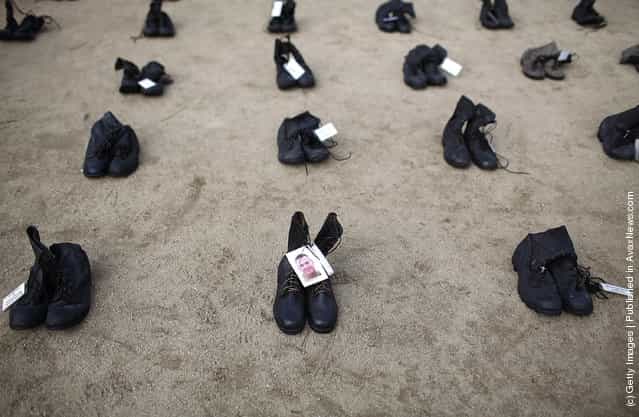A photograph is displayed on a pair of combat boots that are part of the Eyes Wide Open exhibit in front of San Francisco City Hall