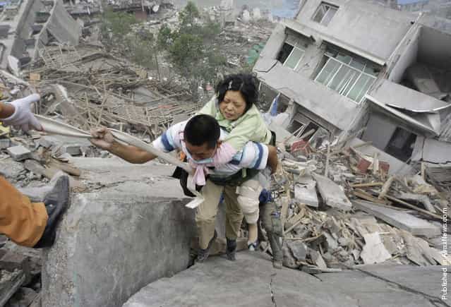 A rescue worker carries a survivor from a collapsed building in the old city district near a mountain at the earthquake-hit Beichuan county, Sichuan province, May 15, 2008