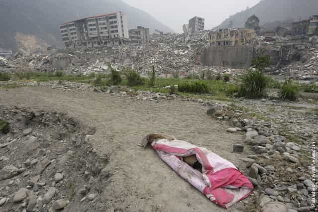 A covered body is laid in front of the ruins of a destroyed old city district, near a mountain at the earthquake-hit Beichuan county, Sichuan province, May 16, 2008