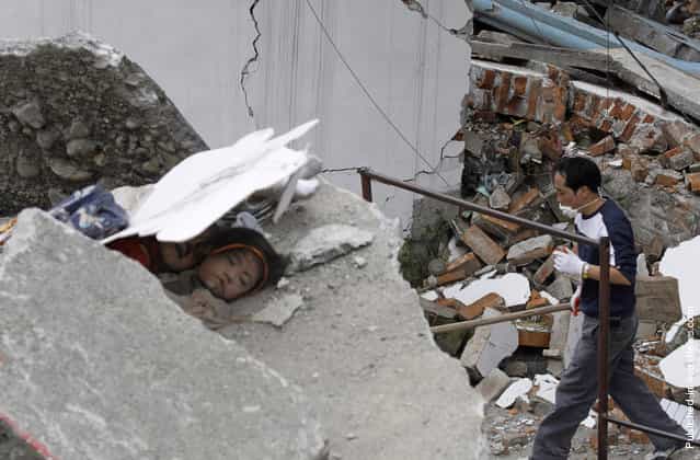A father looking for his child walks past two dead girls who are buried among the ruins of a destroyed primary school in the old city district, near a mountain at the earthquake-hit Beichuan county, Sichuan province, May 15, 2008
