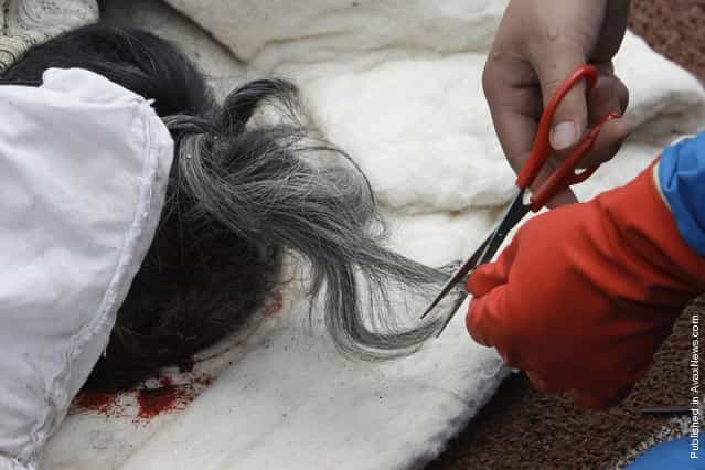 A rescue worker cuts the hair from the body of an elderly woman for identification purposes at the earthquake-hit Hanwang town of Mianzhu county, Sichuan province, May 14, 2008