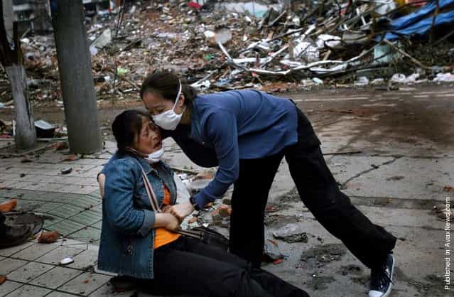 A Chinese woman is helped by a stranger as she collapses after viewing the site of her familys home for the first time since the earthquake on May 12 in the town of Hanwang May 25, 2008