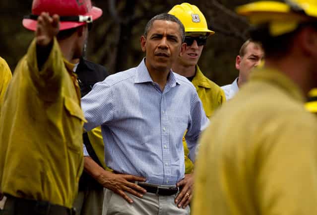 President Barack Obama talks with firefighters as he tours the Mountain Shadow neighborhood devastated by a wildfire in Colorado Springs, on June 29, 2012. After declaring a "major disaster" in the state early Friday and promising federal aid, President Obama got a firsthand view of the wildfires and their toll on residential communities. (AP Photo/Carolyn Kaster)
