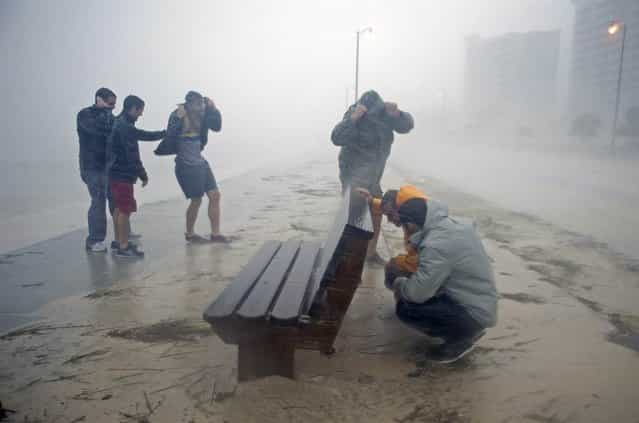 Kyle Taylor and his father Robert Taylor, right, seek shelter behind a bench along Beach Blvd. in Gulfport, Miss., on Aug. 29 as Hurricane Isaac passes through. (Photo by Michael Spooneybarger/Reuters)