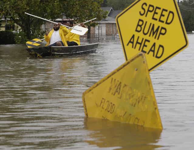 Isaac Fields and Victor Jones use street signs to paddle out of their flooded neighborhood on Aug. 30 in LaPlace, La. (Photo by Eric Gay/AP)