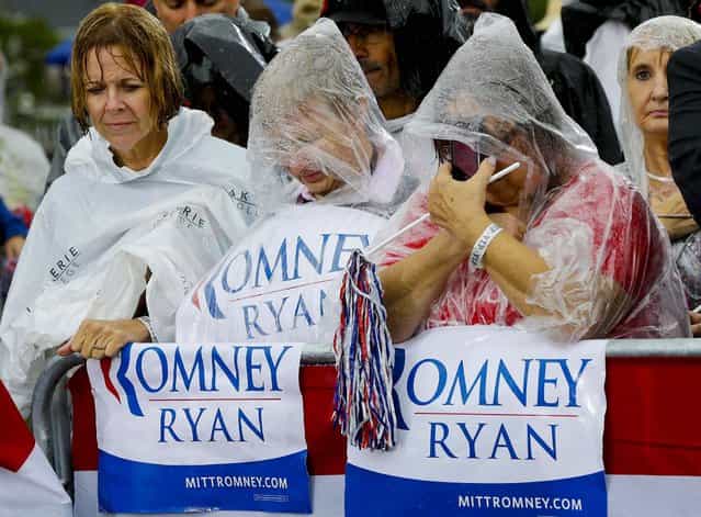 Supporters bow their heads as Republican presidential candidate and former Massachusetts Governor Mitt Romney holds a moment of silence for the embassy officials killed in Libya, as he campaigns in the rain at Lake Erie College in Painesville, Ohio. (Photo by Charles Dharapak/Associated Press)