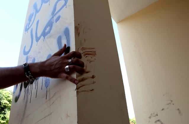 A man explains that the bloodstains on the column are from one of the American staff members who grabbed the edge of the column while he was evacuated after the attack that killed four Americans, including Ambassador Chris Stevens, on Tuesday night in Benghazi. The Arabic writing on the column reads [Villa of Jamal al Beshary], which was written by the owner to protect the property from another attack. (Photo by Mohammad Hannon/Associated Press)