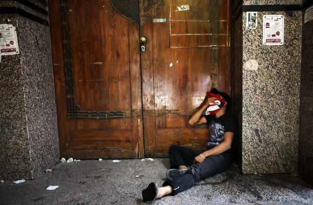 A protester tries to recuperate from tear gas inhalation during clashes with police in Cairo. (Photo by Tara Todras-Whitehill/The New York Times)