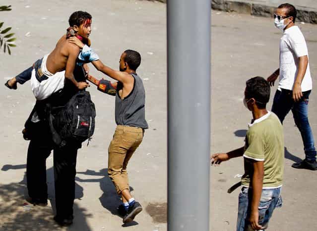 Egyptian protesters evacuate an injured youth toward a waiting ambulance during clashes with security forces near the U.S. Embassy in Cairo, Egypt, on September 14, 2012. (Photo by Nasser Nasser/Associated Press)