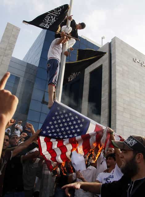 Tunisian protesters lower and burn an American flag as they replace it with an Islamic flag during a demonstration against a film deemed offensive to Islam, outside the U.S. Embassy in Tunis on September 12, 2012. (Photo by AFP)