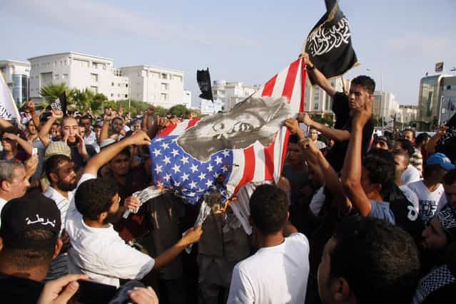 Tunisian protesters lower and burn an American flag as they replace it with an Islamic flag during a demonstration against a film deemed offensive to Islam, outside the U.S. Embassy in Tunis on Sept. 12. A purported portrayal of the life of the Prophet Mohammed in the low-budget [Innocence of Muslims] movie sparked protests all around the Middle East this week. (Photo by AFP)