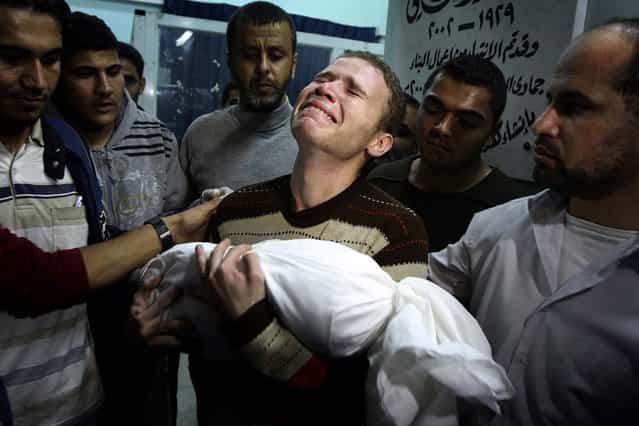 Jihad Masharawi weeps while he holds the body of his 11-month old son Ahmad following an Israeli air strike in Gaza City on Wednesday. (Photo by Majed Hamdan/Associated Press)
