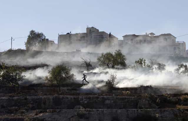 A Palestinian stone-thrower runs after Israeli security forces fired tear gas during clashes against Israel's military operation in Gaza, outside Ofer prison near the West Bank city of Ramallah November 15, 2012. A rocket fired from the Gaza Strip landed close to Tel Aviv on Thursday, in the first attack on Israel's biggest city in 20 years, raising the stakes in a military showdown between Israel and the Palestinians that is moving towards all-out war. (Photo by Mohamad Torokman/Reuters)