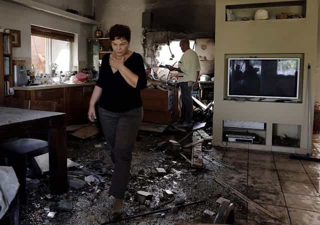 An Israeli woman walks through a damaged house near the Israel-Gaza border. The house was hit Friday by a rocket fired from the Gaza Strip as fierce clashes between Israeli forces and Gaza militants are continue for a third day. (Photo by Tsafrir Abayov/Associated Press)